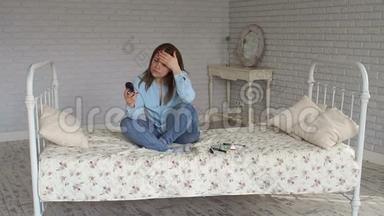 一个悲伤的女人坐在床上，手里拿着<strong>血糖</strong>仪。 高<strong>血糖</strong>。