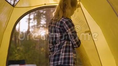 少女在阳光明媚的森林里打开窗户露营帐篷。 在黄色露营帐篷里的年轻旅游女孩在森林徒步旅行