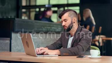 帅哥，时髦的男商人，用电脑上网聊天，坐在咖啡馆的桌子上