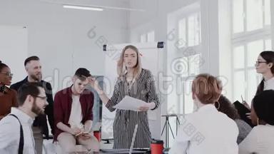 年轻自信，美丽的金发老板女人在现代轻办公室会议慢动作红色EPIC与同事交谈。