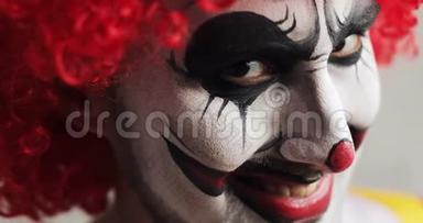 恐怖小丑恶狠狠地斜视着镜头，脸上露出恐怖的微笑，特写镜头。