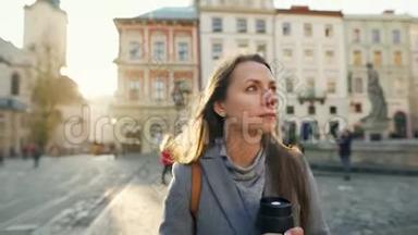 女人手里拿着一个保温杯，走在街上，欣赏日落时分的古城建筑