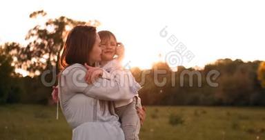 儿子亲吻母亲坐在夕阳下的田野里拥抱和慈爱的母亲。 妈妈`今天。