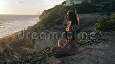 迷人的年轻女孩做瑜伽冥想。 日落海岸概念慢运动。 日落时分约吉人祈祷