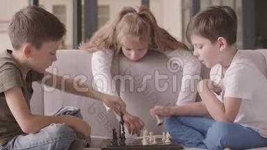 孩子们坐在家里的沙发上下棋。 兄弟<strong>姐妹花</strong>时间在室内。 幸福的家庭，无忧无虑的童年