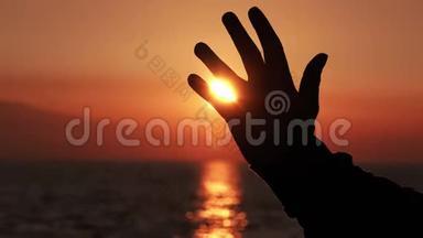 男子举起手臂和手在海滩日落