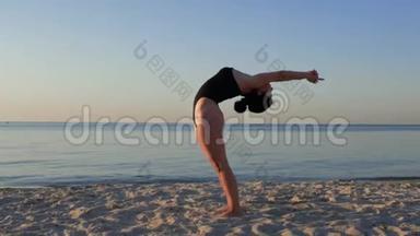 运动的女人穿着黑色紧身衣，在令人惊叹的<strong>日</strong>出时在海边做<strong>瑜伽</strong>。 <strong>健身</strong>、运动、<strong>瑜伽</strong>和健康生活方式