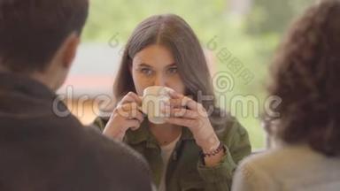 一个可爱的女孩坐在朋友陪伴的餐馆里的肖像。 小可爱喝茶或咖啡。