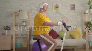 积极积极的祖母耳机听音乐和参与一个固定的自行车关闭
