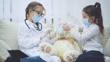 两个<strong>小女孩</strong>和白色泰迪熊坐在沙发上戴着医疗面具。 <strong>医生给</strong>熊一片药。