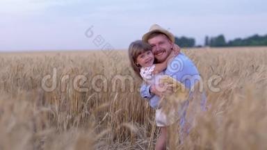 家庭关系，快乐的男人快乐地拥抱快乐的小女孩，在成熟的时候用成熟的小麦在田野上微笑