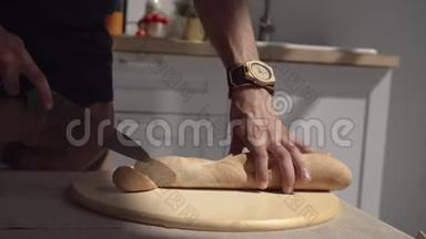 厨师在木板上切面包。 男厨师在木切割板上切片面包的特写。 切面包。