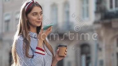 美丽的年轻女子使用智能手机语音识别功能在线站在老城区的街道上，与她交谈