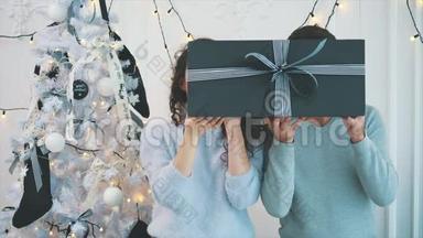 慢动作视频：人们把脸藏在带有条纹的灰色礼品盒后，然后展示他们的脸和