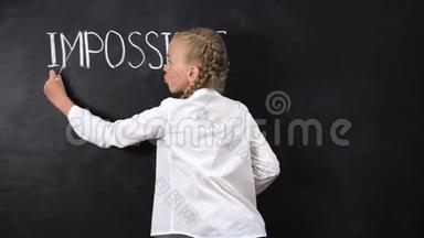 聪明的女孩站在黑板旁边，在单词中跨越IMPOSIBLE，动机