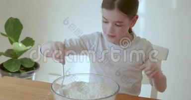 小女孩<strong>小心</strong>翼翼地搅拌一碗面粉和水，用一个大勺子在<strong>玻璃</strong>碗里做面团做面包