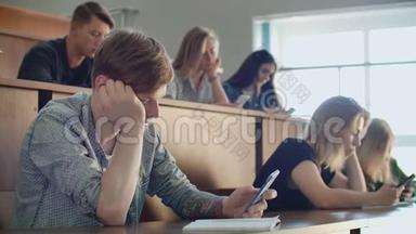 在大学里一堂无聊的讲座，学生们看着智能手机的屏幕。 很多人