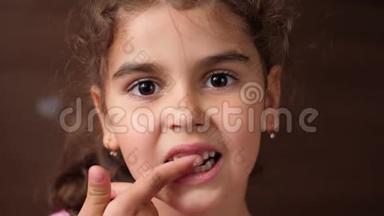 女孩用手指在牙齿被拔掉的地方碰口香糖。 无牙宝宝。 你看看