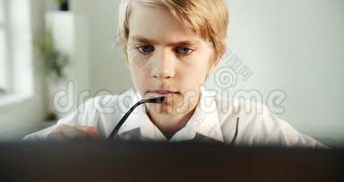 在笔记本电脑上打眼镜的专注男孩