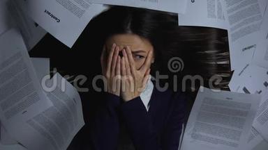 吓得女人捂着脸，看着一堆文件，害怕开工