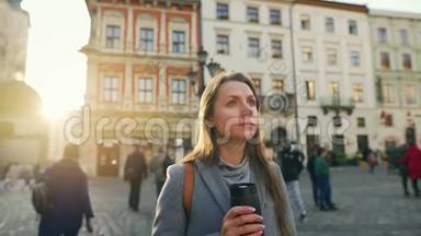 手里拿着保温杯的女人站在街中央，看着她的手表，等待着那个人