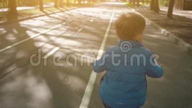 在柏油路骑自行车的小男孩。 可爱的男孩在自行车道上学骑自行车。
