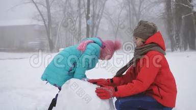 冬季运动会。 两个姐姐在冬天户外堆雪人。