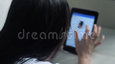 女孩用数字平板电脑制作网上销售购物概念。 黑发女人躺在沙发上看着网上商店付钱