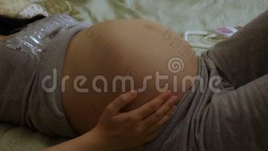 孕妇用多普勒听婴儿`心跳。 孕妇抚摸着她的胃。