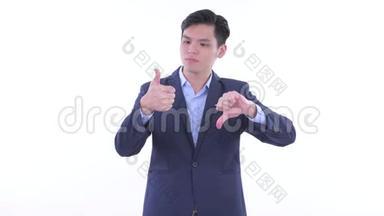 困惑的年轻亚洲商人在竖起大拇指和竖起大拇指之间做出选择