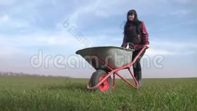农民女孩红脖子在田里工作，穿着橡胶靴的花园手推车。 农<strong>民生</strong>态生活方式农业