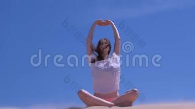 女人舒展着坐在荷花造型的沙滩上放暑假手举着大风天。