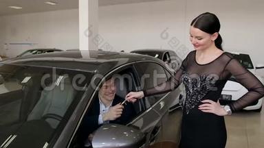 一个穿连衣裙的年轻女孩给了一个男人在陈列室里的<strong>新</strong>车的钥匙。