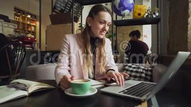美丽的年轻白种人女人喝咖啡，在木桌上的咖啡馆里敲键盘。 的专题