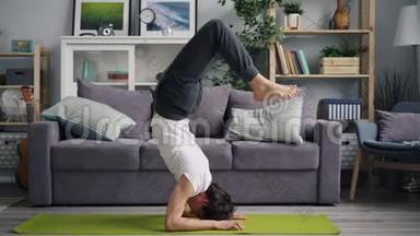 有魅力的亚洲男人在家做瑜伽，手倒立和倒立