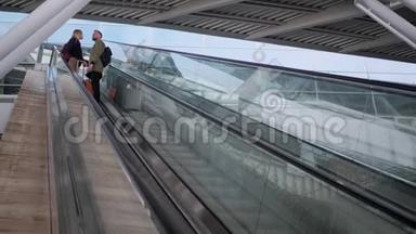 有行李的旅客一对一站在自动扶梯上向下移动