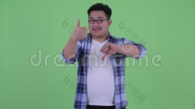 年轻、体重超重的亚洲潮男在竖起大拇指和竖起大拇指之间做出选择