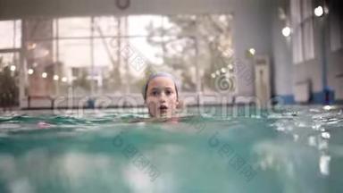 微笑的小女孩没有泳镜在游泳池里水下游泳。 少女在水下潜水。 以上及以上的相片