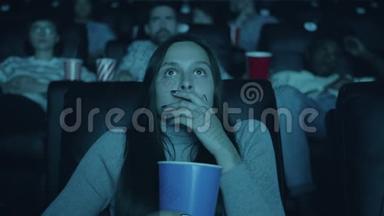恐怖的女人在看恐怖电影时张口拿着爆米花