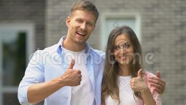 一对微笑的夫妇站在房子外面，房<strong>地产中介</strong>