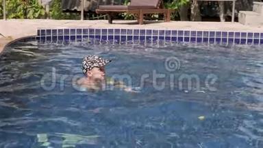 穿着袖子和帽子的小男孩正在度假时在<strong>游泳</strong>池里<strong>游泳</strong>。 男孩在热带的<strong>游泳</strong>池里<strong>游泳</strong>