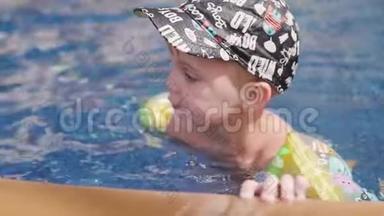 穿着袖子和帽子的小男孩正在度假时在<strong>游泳</strong>池里<strong>游泳</strong>。 男孩在热带的<strong>游泳</strong>池里<strong>游泳</strong>