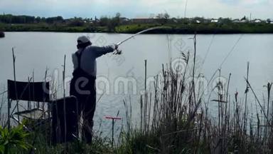 女人钓鱼和把钓鱼竿扔到湖里的剪影。 后景。