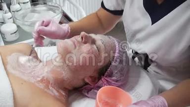 美容师在一名成年妇女的脸上涂上刷子的<strong>洁面乳</strong>