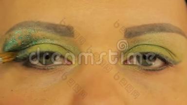 女人`眼睛上画着明亮的绿色阴影。 一只眼里，一个女人放着多汁的绿色火花
