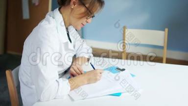 女医生开处方，在医疗办公室的办公桌上填写病史。 国际医生日