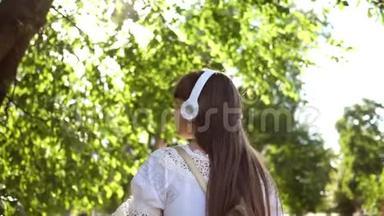 快乐的女人穿着白色连衣裙长发<strong>环游</strong>城市。 慢动作。 带背包的女孩在公园里散步