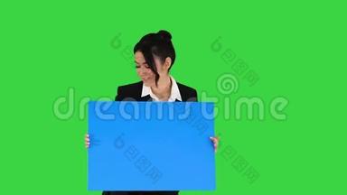 一个时尚的女人在绿色的屏幕上跳舞，拿着空海报，<strong>蓝色</strong>的模型。