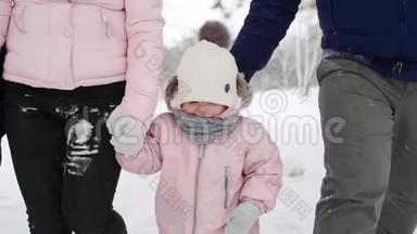 穿暖和连衣裙的婴儿脚做第一步。 孩子学会走路。 友好的全家人在冬季森林散步