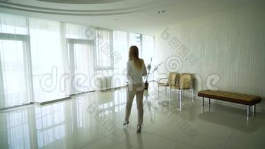 在带杯子的办公室大厅里，金发女人穿着高跟鞋走路的后景